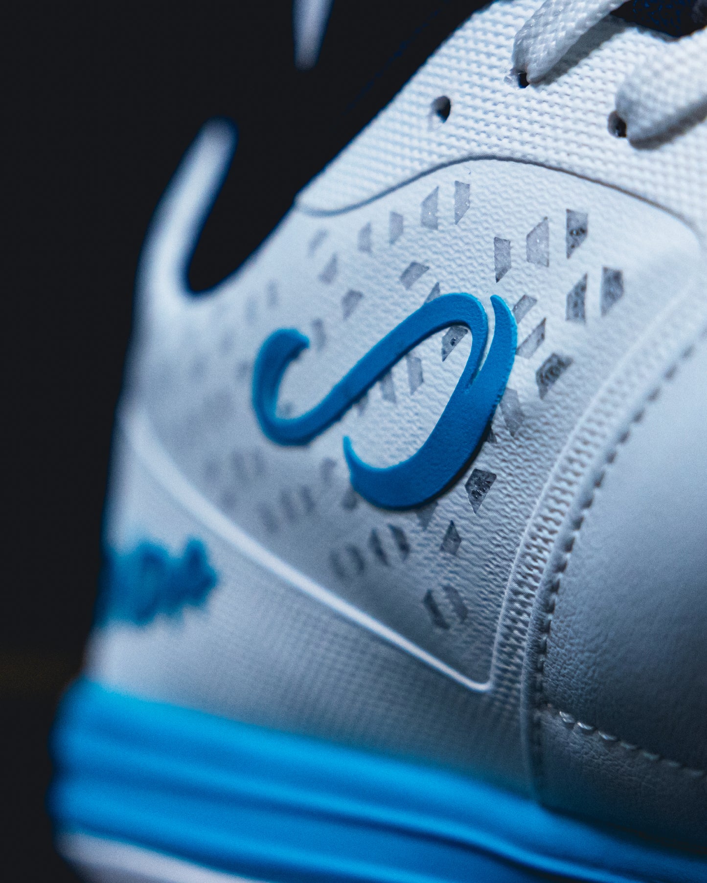 Close-up of the SENDA logo on White Blue Ushuaia Pro 2.0 futsal shoe, showcasing breathable TPU mesh and textured upper for enhanced flexibility and performance grip.