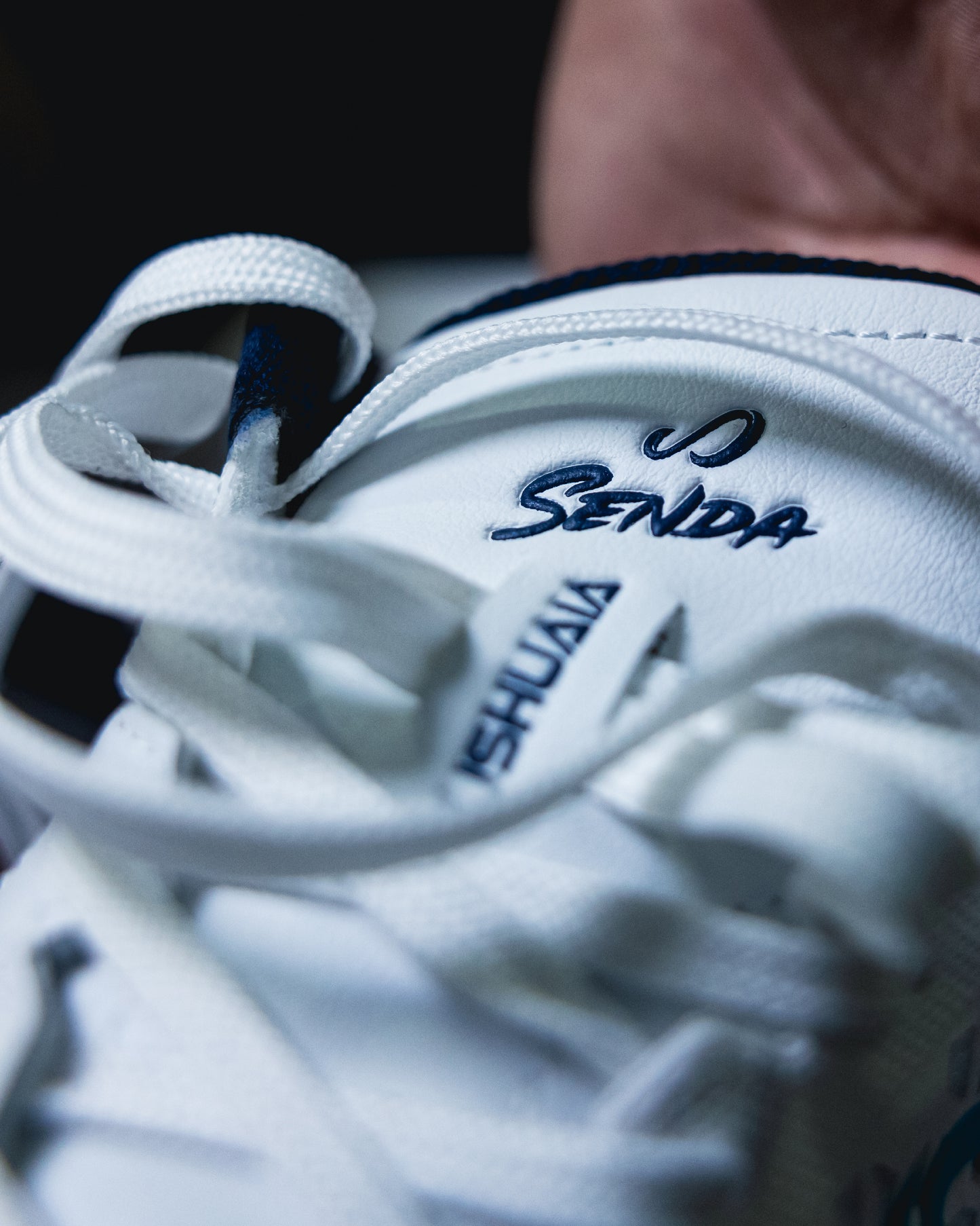 Close-up of the tongue and branding on the White Blue Ushuaia Pro 2.0 futsal shoe by SENDA, highlighting the embossed logo and secure lacing system for optimal fit.