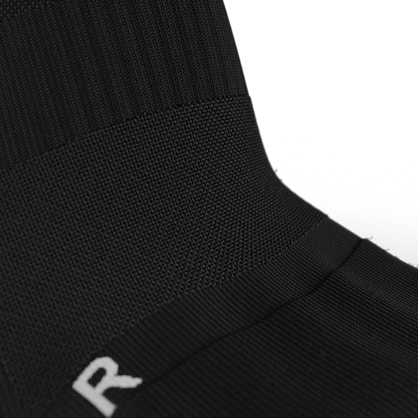 Detailed close-up of the arch support compression band on the Senda Gravity Pro Grip Socks in black, designed for stability and comfort during play.