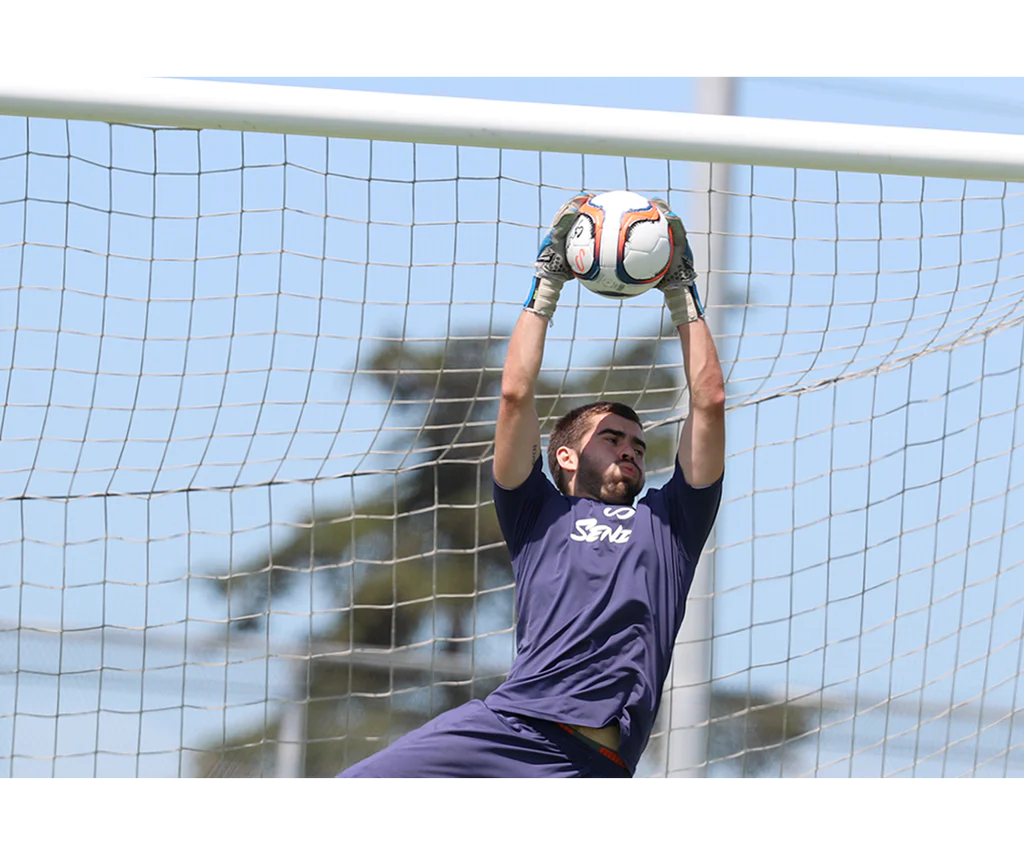 Goalkeeper catching Senda Valor Premium Soccer Ball during a save at goalpost in live match scenario.