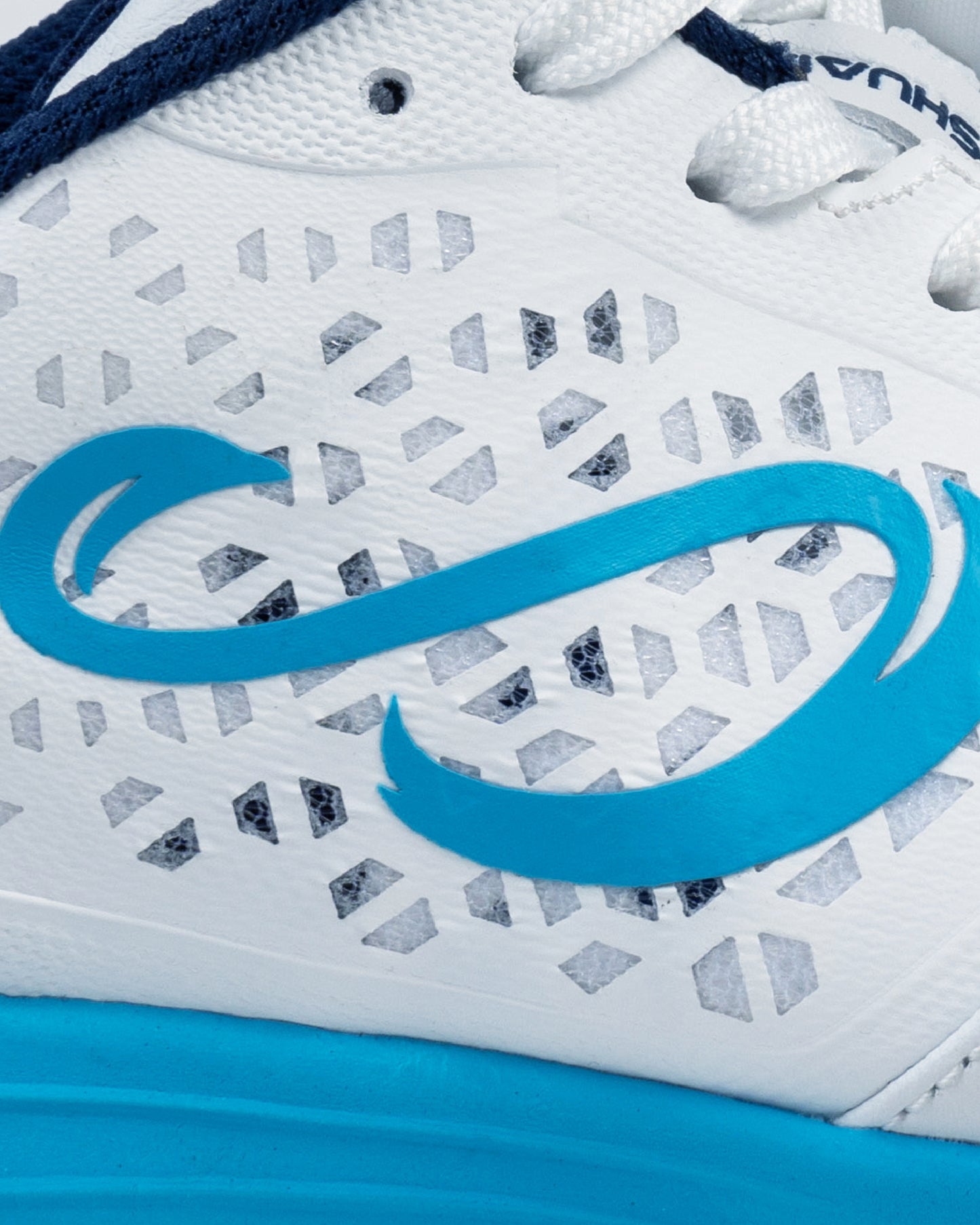 Close-up of Senda logo on white Ushuaia Club 2.0 futsal shoe, showing textured breathable synthetic upper with diamond-cut perforations and blue detailing.

