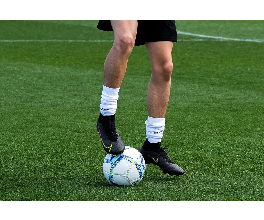 Close-up view of a soccer player controlling the Senda Apex Match Soccer Ball on a grassy field, showcasing grip and control during play.







