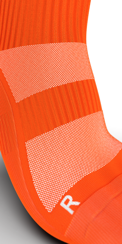 Close-up of Senda Gravity Pro orange sock showing mesh ventilation and arch compression for enhanced fit.

