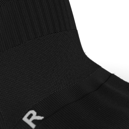 Detailed close-up of the arch support compression band on the Senda Gravity Pro Grip Socks in black, designed for stability and comfort during play.

