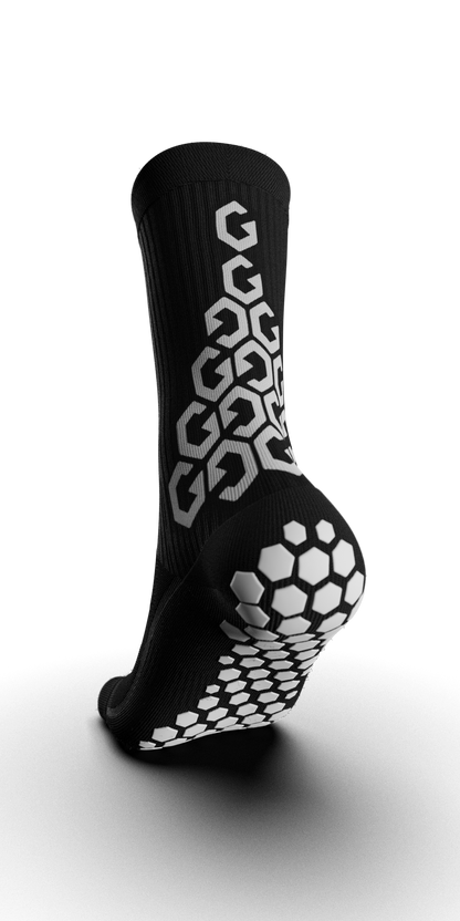 Angled view of Senda Gravity Pro Grip Socks in black, highlighting rear hex traction pods and vertical grip pattern for explosive movement and balance.

