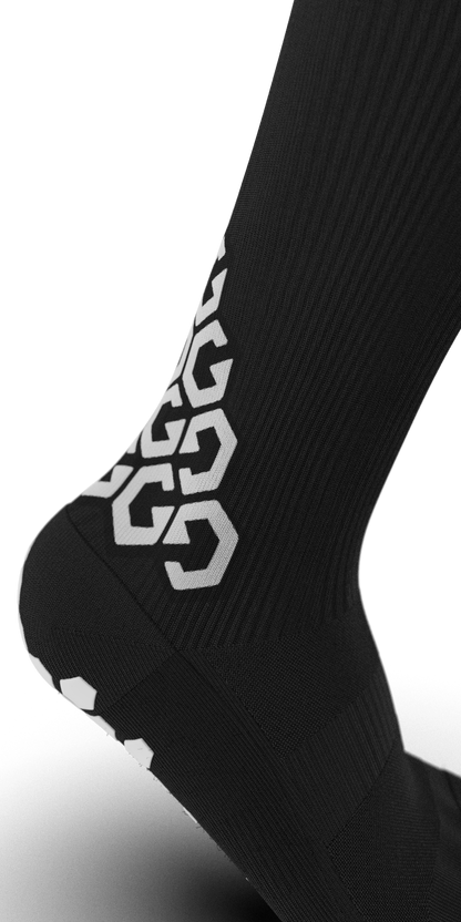 Side angle of Senda Gravity Pro Grip Socks in black featuring bold G-pattern branding and ribbed compression zones for snug arch support and mobility.

