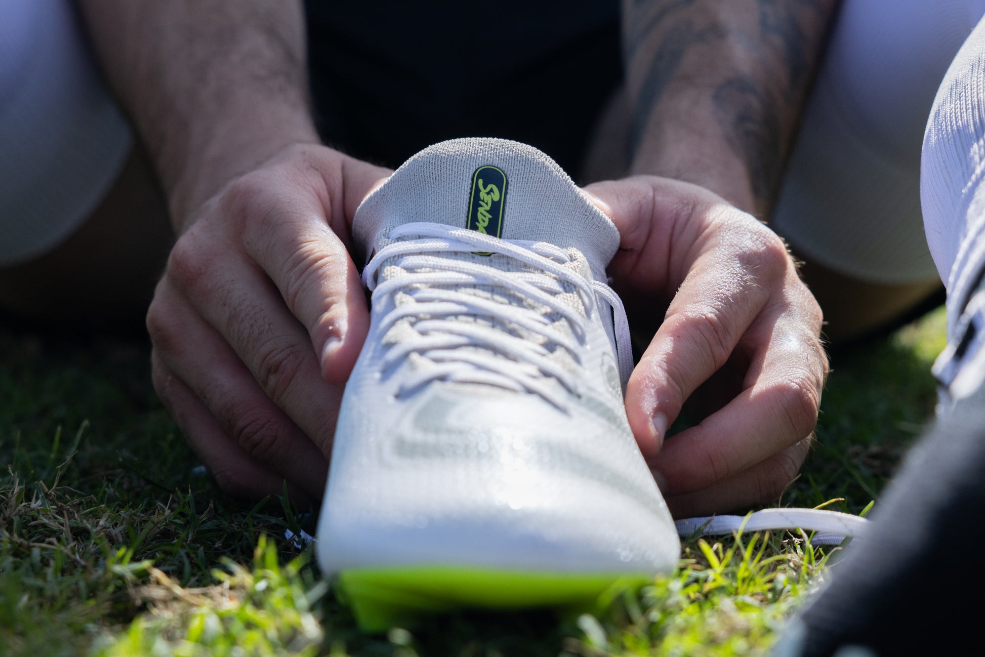 Close-up of hands adjusting laces on the Senda Pampa Pro Soccer Cleats, highlighting comfort and fit.

