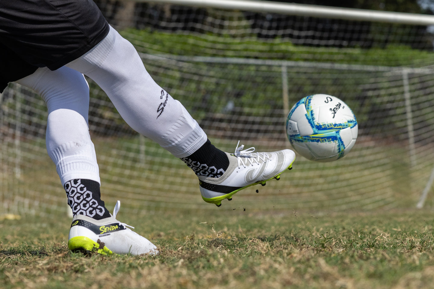 Soccer player striking a ball while wearing Senda Pampa Pro Soccer Cleats, highlighting stud traction and dynamic movement on the field.


