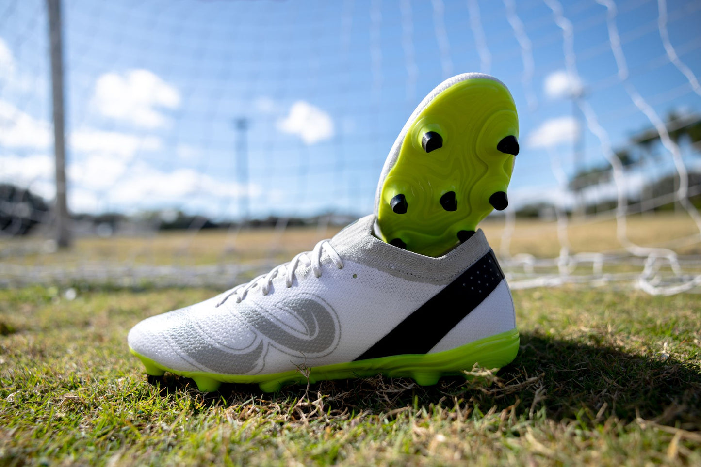 Side and sole view of Senda Pampa Pro Soccer Cleats on a grass field showing stud configuration and grip design.

