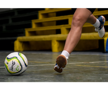 Close-up of player striking the Senda Rio Match Futsal ball on an indoor surface during a game.

