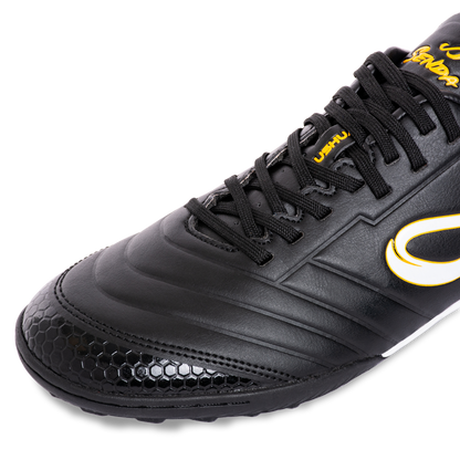 Closeup front angle of Senda Ushuaia Academy Turf Black featuring honeycomb textured toe and black synthetic upper.

