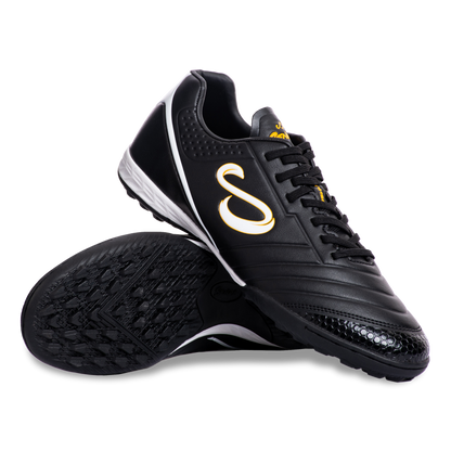 Pair of Senda Ushuaia Academy Turf Black shoes displayed with sole and side view showing grip pattern and bold S logo.

