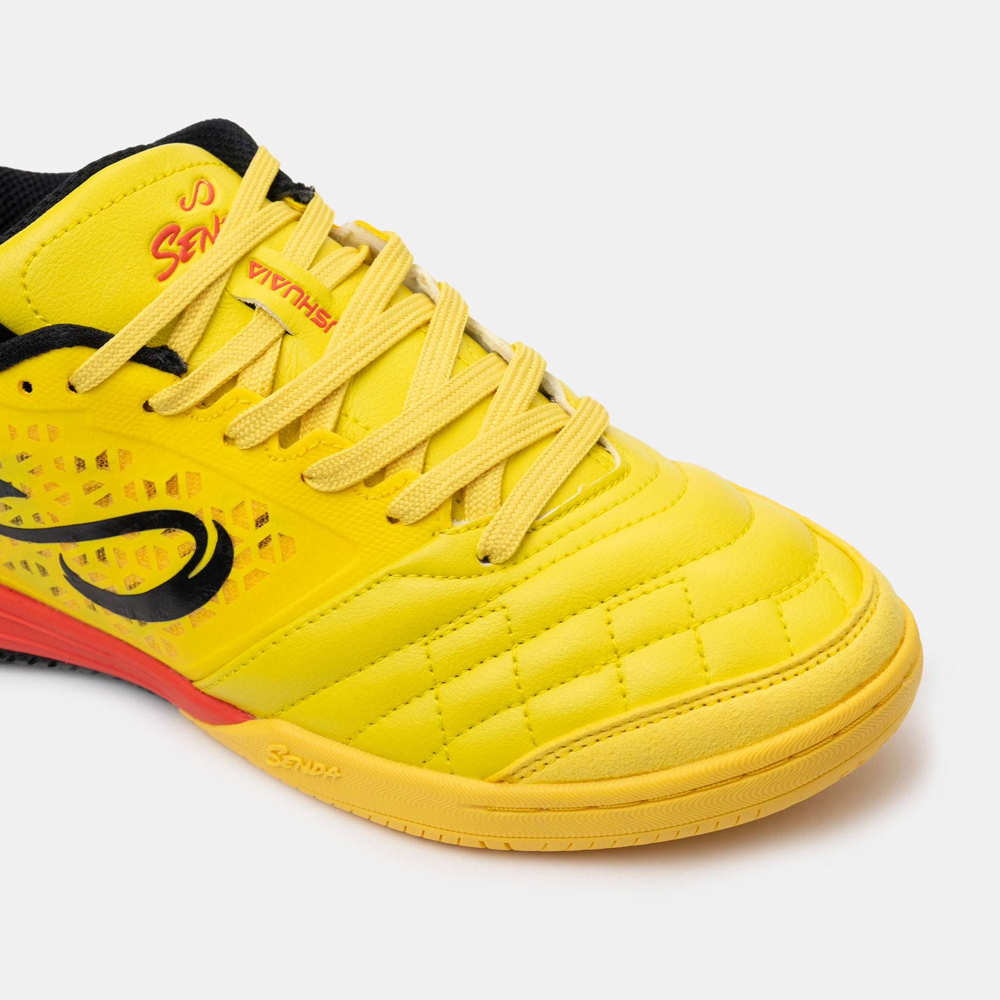Close-up of Senda Ushuaia Pro 2.0 yellow futsal shoes showing reinforced toe stitching and breathable side panels.

