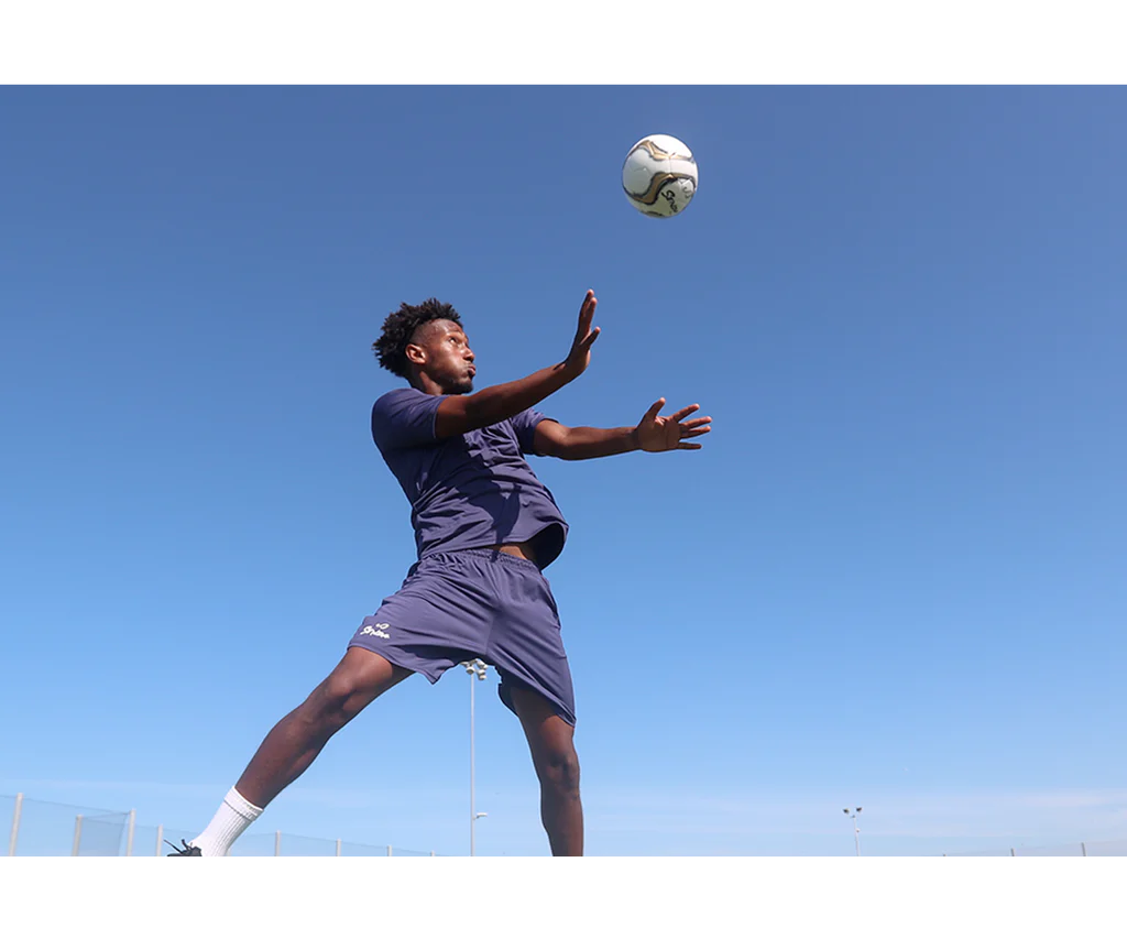 Soccer player leaping mid-air to head the Senda Volta Professional Soccer Ball during outdoor play, emphasizing agility and in-game performance.

