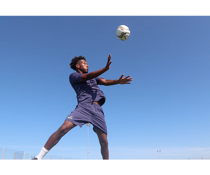 Soccer player leaping mid-air to head the Senda Volta Professional Soccer Ball during outdoor play, emphasizing agility and in-game performance.

